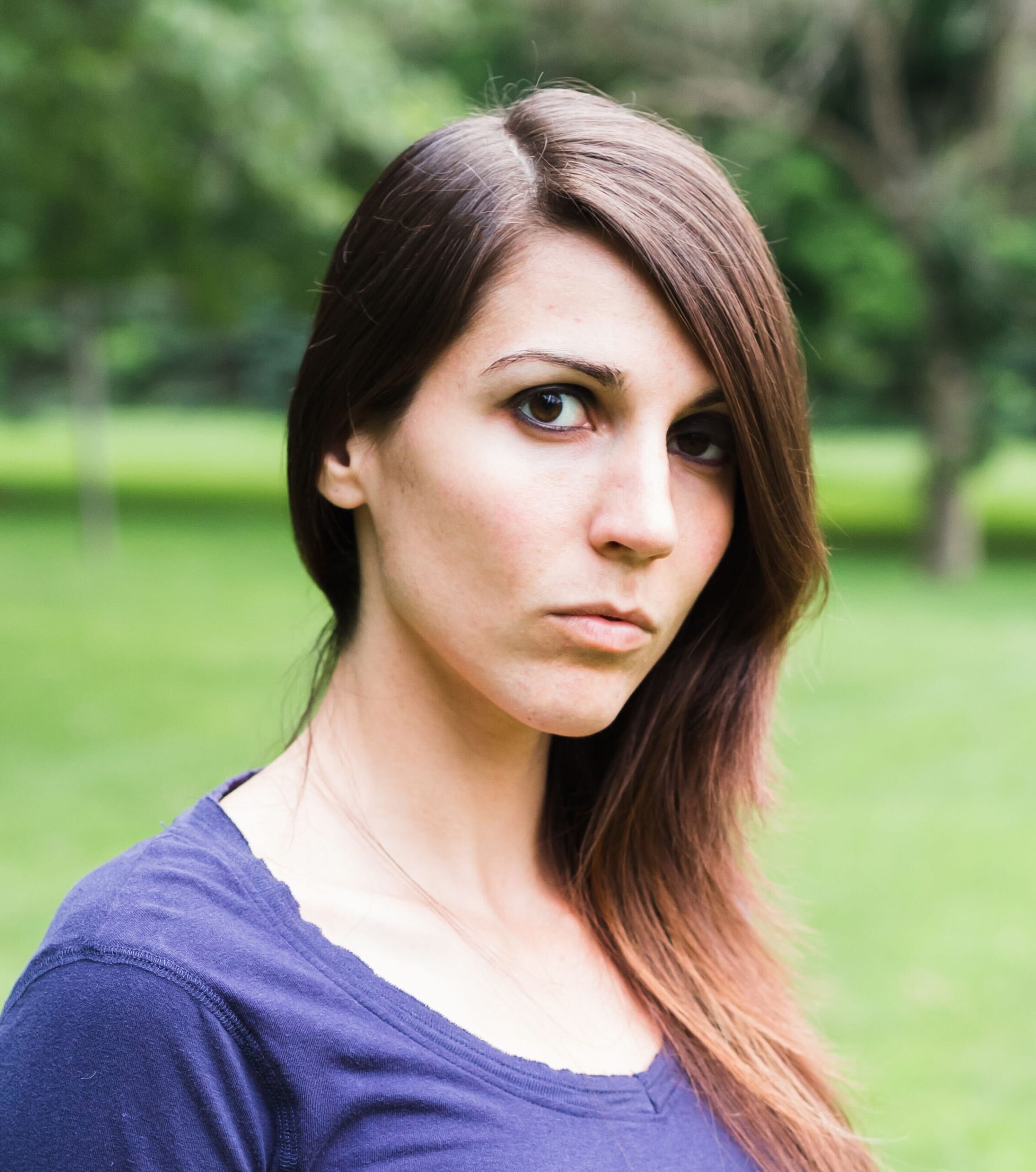 Woman with dark hair looking at camera with head slightly turned and a more serious face.